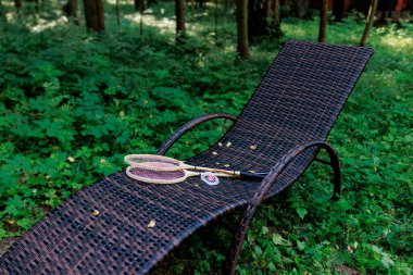 Beyaz badminton topu ve iki raket parktaki bir şezlongda yatıyor. Boş zaman, eğlence, raket sporları. Yüksek kalite fotoğraf