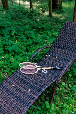 Beyaz badminton topu ve iki raket parktaki bir şezlongda yatıyor. Boş zaman, eğlence, raket sporları. Yüksek kalite fotoğraf