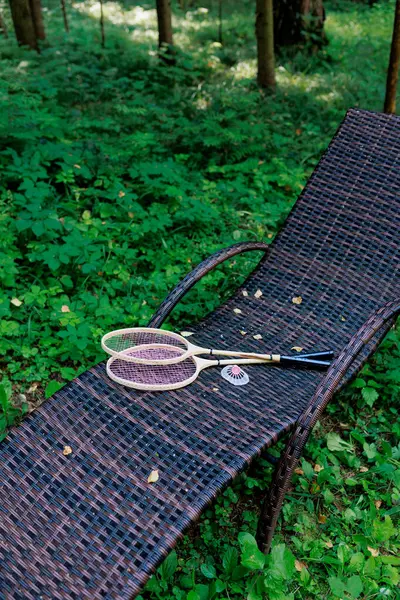 Beyaz badminton topu ve iki raket parktaki bir şezlongda yatıyor. Boş zaman, eğlence, raket sporları. Yüksek kalite fotoğraf