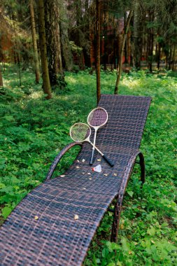 Beyaz badminton topu ve iki raket parktaki bir şezlongda yatıyor. Boş zaman, eğlence, raket sporları. Yüksek kalite fotoğraf