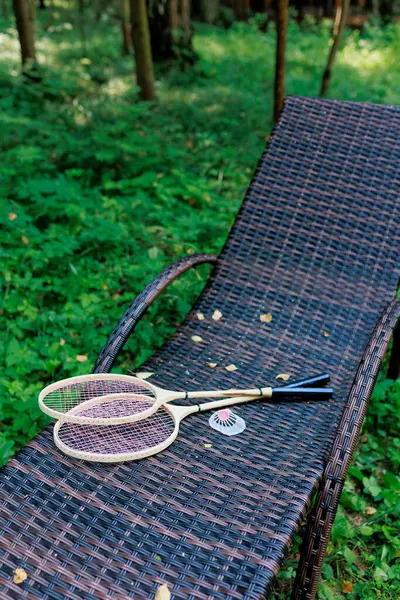 Beyaz badminton topu ve iki raket parktaki bir şezlongda yatıyor. Boş zaman, eğlence, raket sporları. Yüksek kalite fotoğraf
