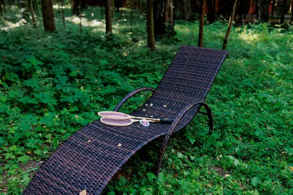 Beyaz badminton topu ve iki raket parktaki bir şezlongda yatıyor. Boş zaman, eğlence, raket sporları. Yüksek kalite fotoğraf