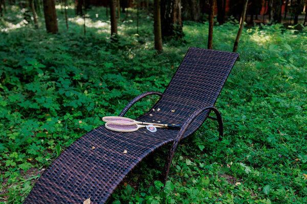 Белый шаттл бадминтона и две ракетки лежат на шезлонге в парке. Отдых, отдых, ракетный спорт. Высокое качество фото