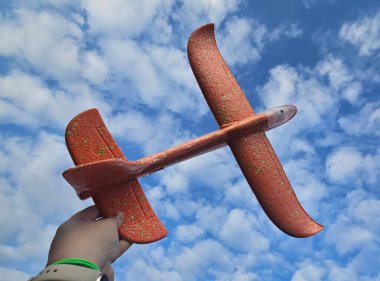 Orange toy plane in blue sky  clipart