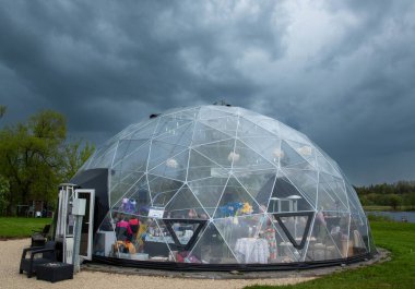 Bulutlu gökyüzünün arka planında büyük cam bir top olan gölün kubbesi..