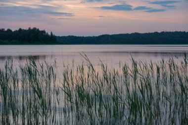 Gün batımını gölün üzerinde, ön planda suyla.