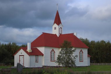 Karasjok, Finnmark, Norveç 'teki tarihi ahşap kilise, dramatik bulutlu bir gökyüzüne karşı beyaz duvarlar ve kırmızı bir çatı içeriyor. Kuzey mirası ve geleneksel mimariyi yansıtan barışçıl bir manzara