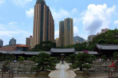 Hong Kong 'daki Chi Lin Nunnery' nin sakin avlusunda geleneksel Çin mimarisi, manikürlü bonsai ağaçları ve parlak mavi gökdelenler altında modern gökdelenler yer alıyor.
