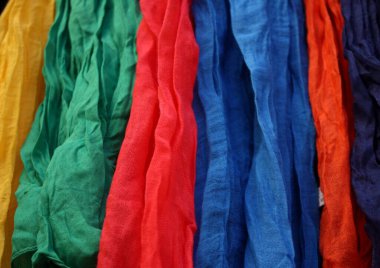 Bangkok, Tayland 'daki Chatuchak Haftasonu Pazarı' nda sergilenen renkli eşarp ve kumaşlar, kırmızı, mavi, yeşil ve sarı renkli canlı tonlara sahip.