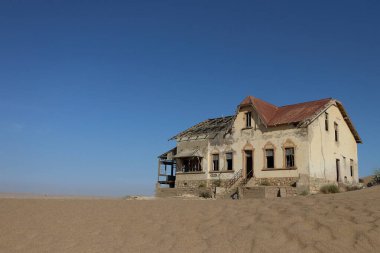 Kolmanskop, Namibya - 13 Eylül 2019: Luderitz 'in dışındaki hayalet şehir Kolmanskop' ta terk edilmiş binalar, bir zamanlar gelişen elmas madenciliği yerleşkesi, şimdi Namib Çölleri tarafından ele geçirildi.