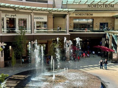 Salt Lake City, Utah, ABD - 29 Eylül 2024: Dekoratif bir su çeşmesi, lüks perakende mağazaları ve cam kaplı bir avlunun altında yürüyen müşteriler