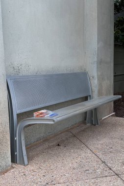 Metal bir bankta beton bir duvara yapıştırılmış hamur işleri içeren mühürlü plastik bir beslenme çantası, kentsel alanda unutulmuş bir yemeği akla getiriyor..
