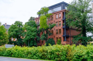 Sayısız penceresi olan önemli, büyük bir tuğla bina ağaçlar ve canlı çalılarla güzelce çevrelenmiştir.