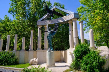 Kuşu nazikçe tutan bir adamı resmeden güzel bir heykel zarif sütunlar ve yemyeşil ağaçlarla çevrilidir.