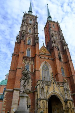 Önünde göze çarpan bir heykel bulunan büyük bir kilise binası var, önemli bir görsel temsil oluşturuyor.