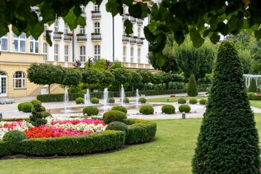 Canlı çiçeklerle dolu çok güzel bir bahçe var ve çok güzel bir binanın önünde çalılar var.