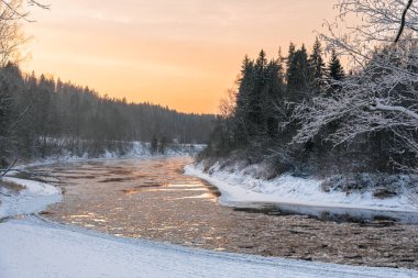 Gauja nehri, Sigulda, Letonya 'da gün batımında soğuk ve karlı bir kış akşamı.