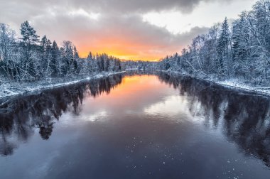 Gauja nehri karlı kış akşamında Sigulda, Letonya 'da gün batımında