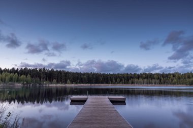 Bahar akşamında orman gölünde ahşap iskele
