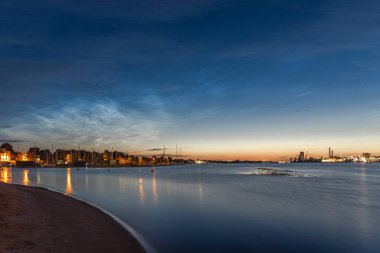 Temmuz gecesi Letonya 'nın Riga kentindeki Kipsala adasındaki Daugava nehrinin üzerindeki gece bulutları. Uzun pozlu fotoğrafçılık.