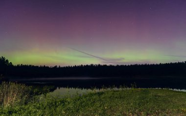 Aurora Borealis Eylül gecesi Letonya 'daki orman gölü üzerinde kuzey ışıkları. Ön planda ahşap iskele.