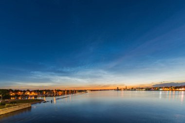 Haziran gecesi Letonya 'nın Riga kentindeki Kipsala adasındaki Daugava nehri üzerindeki gece bulutları.