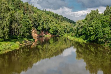 Güneşli bir Temmuz gününde Letonya 'nın Sigulda kentindeki Gauja nehri üzerindeki kırmızı kumtaşı 