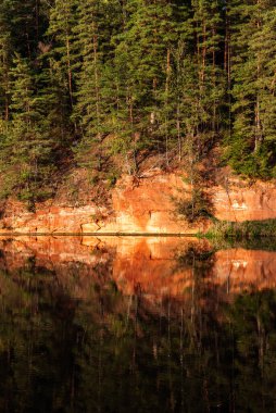 Red sandstone cliffs on Brasla river in Latvia in September clipart