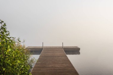 Göl kıyısındaki ahşap iskele kalın sisle kaplıydı.
