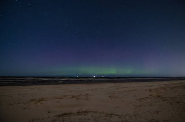 Zayıf Aurora Borealis... İlkbaharda Letonya 'da Baltık Denizi sahilinde kuzey ışıkları...