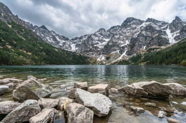 Saf alp gölü Morskie Oko (çeviri: Sea Eye) Polonya 'nın vahşi doğasındaki dramatik Tatra dağ zirveleriyle çevrilidir..