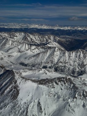 Fotoğraf, Colorado 'daki karlı bir dağ sırasının nefes kesici bir görüntüsünü yakalıyor. Tıpkı bir uçak penceresinden göründüğü gibi. Uçsuz bucaksız tepeler, karla kaplı araziye yayılmış, yukarıdaki canlı mavi gökyüzü, Alp 'in manzaralı güzelliğini artırıyor.