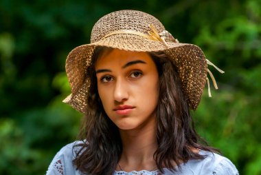 Yazlık şapkalı ve mavi bluzlu neşeli gülüşlü genç bir kadın doğanın tadını çıkarıyor..