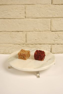 Mermer tabakta servis edilen lezzetli Türk lokumu. Geleneksel tatlı ikramının yakın çekimi yumuşak dokusunu ve pudra şekerli kaplamasını sergiliyor ve klasik bir Türk mutfağı unsurunu temsil ediyor..