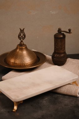 Boş bir mermer tabağı ve Türk kahve öğütücüsüyle rafine ve zarif bir kompozisyon oluşturan minimalist bir yemek tasarımı..