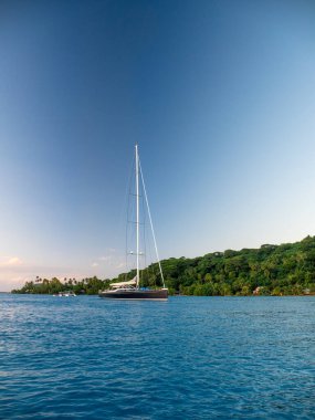 Yacht anchored in blue waters of Bora Bora at sunset clipart