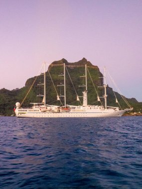 Windstar sail boat anchored in blue waters of Bora Bora at sunset clipart