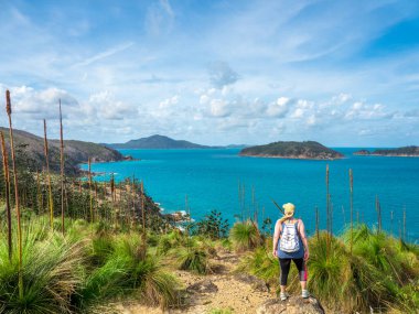 Hamilton Adası 'nda yürüyüş yolunda yürüyen bir kadın, Queensland Avustralya' nın WhitSunday 'deki manzarasına hayran.