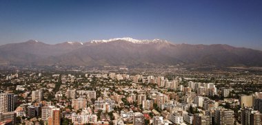 Una vista impresionante de Santiago se despliega bajo la imponente cordillera de los Andes, cuyos picos nevados se alzan como guardianes silenciosos de la ciudad. Aqu se muestra la combinacin de rascacielos modernos y edificios tradicionales.