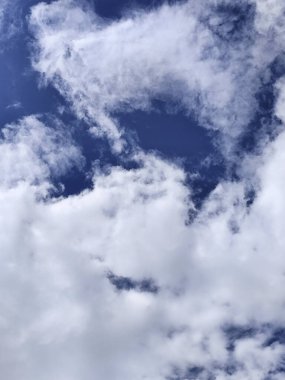 Berrak mavi gökyüzünde yüzen kümülüs bulutlarının sakin görüntüsü yukarıdaki doğa tuvalinde sükunetin ve sükunetin özünü yakalıyor..