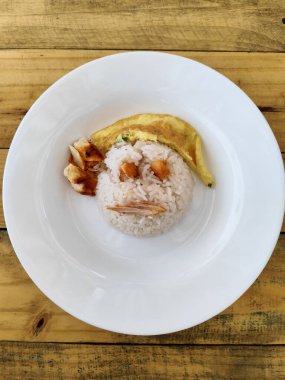 Izgara tavuk parçaları ve omlet ile tamamlanmış, yüz şeklinde beyaz pirinç içeren eğlenceli ve eğlenceli bir yemek.