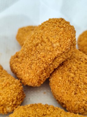 Çıtır desenli altın sarısı tavuk nuggetları, fast food temaları, abur cubur konseptleri ya da menü tasarımları için mükemmel, temiz beyaz arka planda sergileniyor..