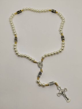 Güzel, beyaz bir inci gerdanlık. Her birimizin içinde gizemlerin ayrıntıları var. İçinde zarif bir haç var..