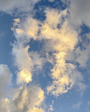 Sabahın erken saatlerinde gökyüzünün sakin bir görüntüsü, mavinin tonlarında, narin beyaz bulutlarla bezenmiş, nazikçe yüzen..