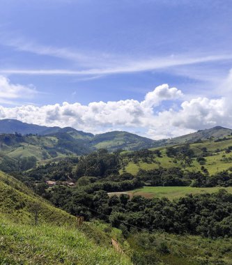 Yumuşak tepeleri ve açık mavi gökyüzü olan yeşil bir manzaranın güzel manzarası..