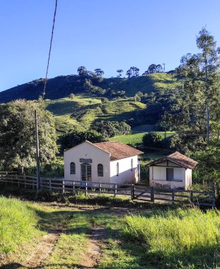 Cunha SP 'nin kırsal kesimindeki küçük kilise. Yeşil bir dağ silsilesindeyiz. Mavi gökyüzü ve aşırı büyümüş tepeler huzur ve resim gibi bir manzara yaratır.