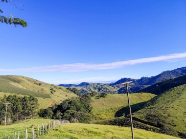 Yumuşak tepeleri ve açık mavi gökyüzü olan yeşil bir manzaranın güzel manzarası..