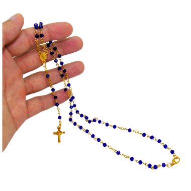 Mavi boncuklardan ve zarif altın aksanlardan oluşan ve ucunda küçük bir haç asılı bir tespih tutan bir el. İmaj, inancı, bağlılığı ve ruhani güzelliği ifade eder..