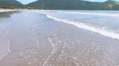 Ubatuba, Brezilya 'daki Ubatumirim Sahili' nde bulutlu bir gökyüzünün altında hafif dalgalar yuvarlanıyor..