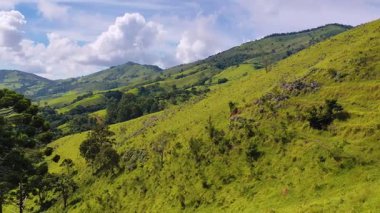 Parlak mavi gökyüzünün altında yemyeşil bir dağın manzarası. Güzel bir sabahta yumuşak beyaz bulutlar..